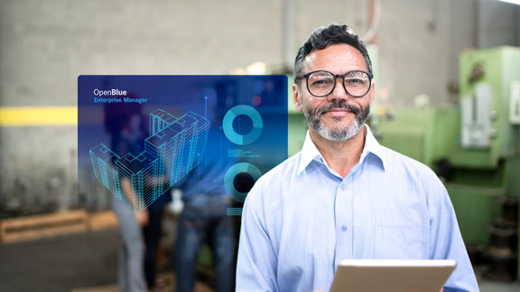 Man using a tablet with an infographic of OpenBlue Enterprise Manager overlaid on the background